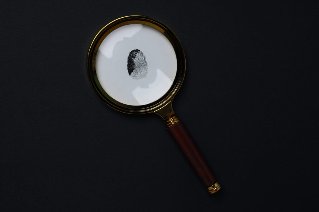 A magnifying glass with a fingerprint in the middle signifying evidence gathering and surveillance.